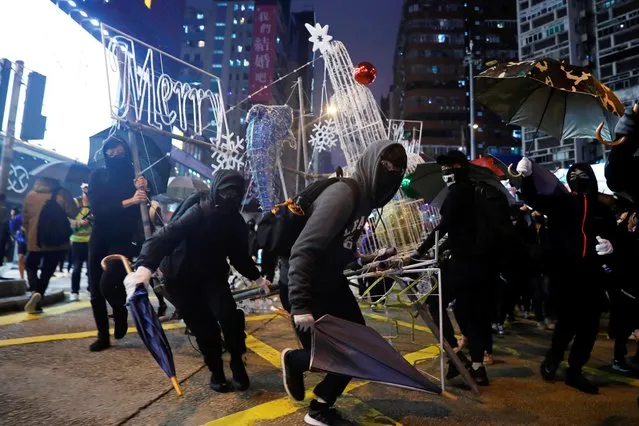 Anti-government protesters tear down Christmas and New Year's decorations during a demonstration on New Year's Eve outside Mong Kok police station in Hong Kong, China on December 31, 2019. Protesters briefly blocked Nathan Road, a key artery leading through Kowloon to the harbor, after forming human chains across the Chinese-ruled city and marching through shopping malls, urging people not to give up the fight for democracy in 2020. (Photo by Tyrone Siu/Reuters)
