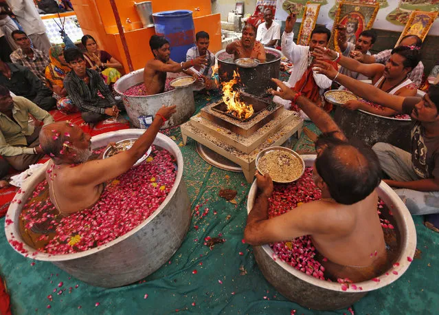 Hindu priests sit in cauldrons of water and make offerings to in front of a fire while performing the “Parjanya Varun Yagam”, a special prayer for rain, in the western Indian city of Ahmedabad July 1, 2014. India's monsoon rainfall was 43 percent below average in June, the weather office said on Monday, the weakest first month of the season in five years. (Photo by Amit Dave/Reuters)