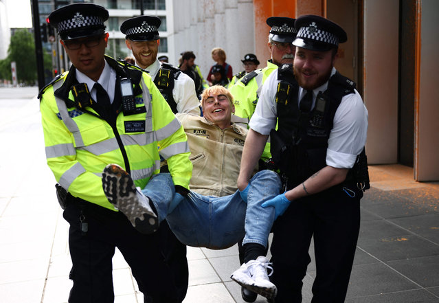 A Just Stop Oil climate activist reacts while being detained after activists threw orange paint at the UK headquarters of TotalEnergies in the Canary Wharf district in London on June 27, 2023 to protest against the construction of the East African Crude Oil Pipeline (EACOP). TotalEnergies and the China National Offshore Oil Corporation (CNOOC) have signed a $10-billion agreement to develop the Ugandan oilfields and build the pipeline. But the project has run into strong opposition from activists and environmental groups that say it threatens the region's fragile ecosystem and the livelihoods of tens of thousands of people. (Photo by Henry Nicholls/AFP Photo)