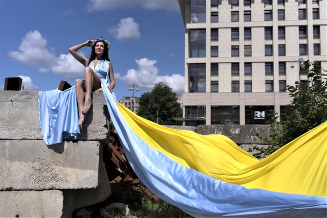 Dressed in the colors of the Ukrainian flag, Maria Berdieva poses for photos to help raise money for Ukrainian troops in Kyiv, Ukraine, Monday, July 10, 2023. (Photo by Jae C. Hong/AP Photo)