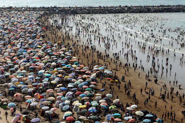 A crowd of people pack the beach in Rabat, Morocco, July 23, 2017. Moroccans and tourists took advantage of beautiful summer weather to enjoy the beach. Morocco welcomed about 3 million tourists during the first four months of the year and is on par to see an increase of about 10 percent over the same time as 2016. (Photo by Abdelhak Senna/EPA)