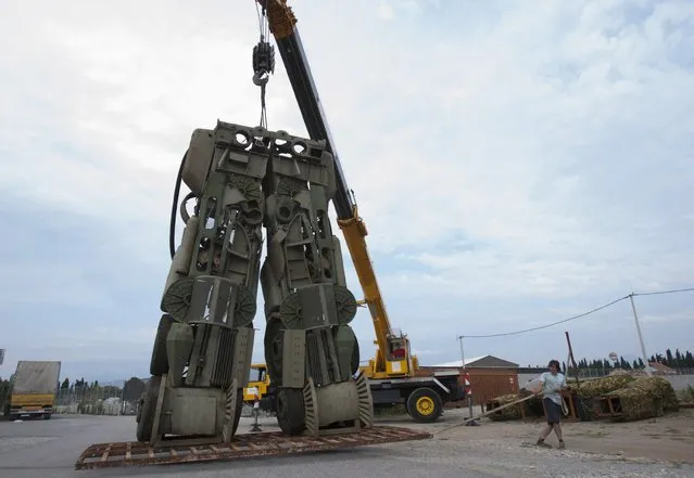 Danilo Baletic, 22, moves the leg section of a “transformer-inspired” sculpture constructed from scrap metal at a junkyard in Podgorica, July 21, 2014. Baletic, 22, makes sculptures of his childhood cartoon heroes “Transformers” from scrap metal. In the last two years, he has made seven “Transformers” that are placed on the streets of Montenegro's capital Podgorica as part of an exhibition called “Transformers defending Podgorica”. (Photo by Stevo Vasiljevic/Reuters)