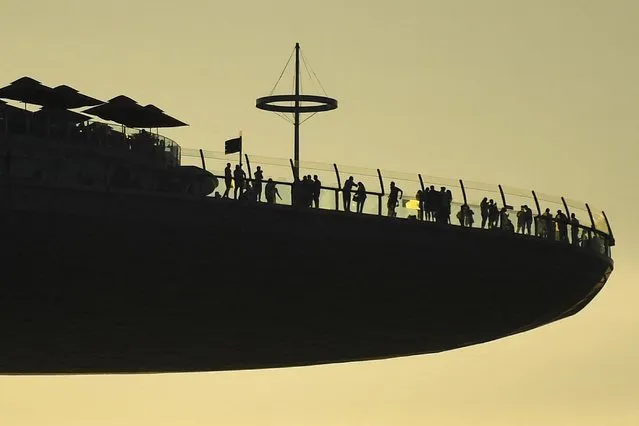 People are silhouetted against the afternoon sun as they view the surroundings from the Marina Bay Sands skypark observation deck in Singapore on June 14, 2022. (Photo by Roslan Rahman/AFP Photo)