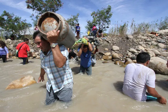 People carry their belongings across the Tachira River from San Antonio del Tachira, Venezuela, toward Colombia, Tuesday, August 25, 2015. (Photo by Eliecer Mantilla/AP Photo)
