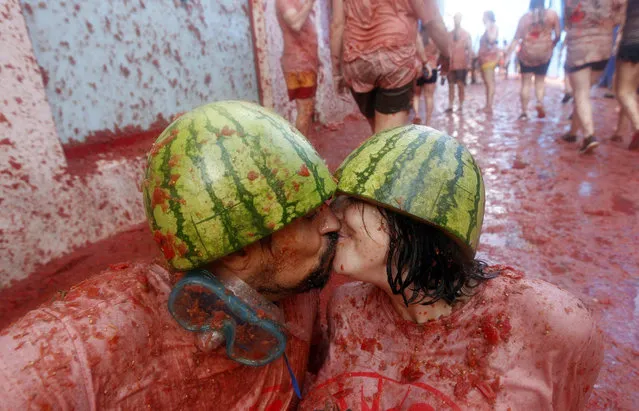 A couple kisses among thousands taking part in the traditional “Tomatina” or tomato battle in Bunol, Spain, 26 August 2015. Crowds throw tons of ripe tomatoes at each other and are soaked with smashed tomatoes and juice in just a few minutes. The worldwide known festival, that has charged an entrance fee during the past three years to limit it's capacity, attracts numerous foreign youths to join in the funny tomato-fight. (Photo by Kai Foersterling/EPA)