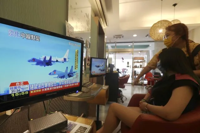A customer and a staff member watch a news report on the recent tensions between China and Taiwan, at a beauty salon in Taipei, Taiwan, Thursday, August 4, 2022. Taiwan canceled airline flights Thursday as the Chinese navy fired artillery near the island in retaliation for a top American lawmaker’s visit. (Photo by Chiang Ying-ying/AP Photo)