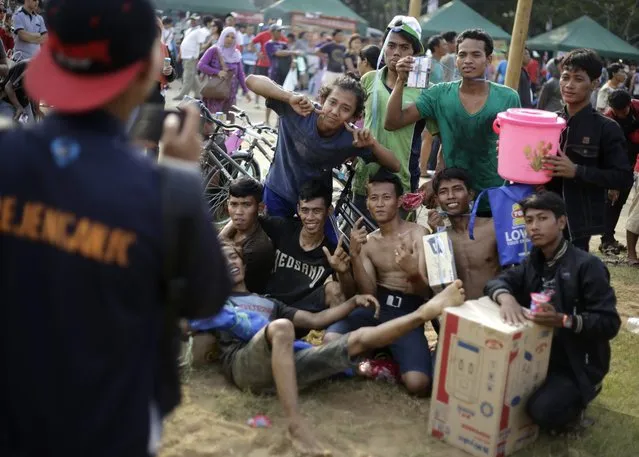 Indonesian men pose for a photo with the prizes they won in a greased-pole climbing competition at the end of the event held as a part of the Independence Day celebrations in Jakarta, Indonesia, Sunday, August 17, 2014. (Photo by Dita Alangkara/AP Photo)