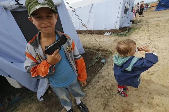 Maxim, 7, who arrived from the eastern Ukrainian town of Horlivla (Gorlovka), poses with a toy gun at a temporary tent camp set up for Ukrainian refugees outside Donetsk, located in Russia's Rostov region near the Russian-Ukrainian border, August 18, 2014. (Photo by Alexander Demianchuk/Reuters)