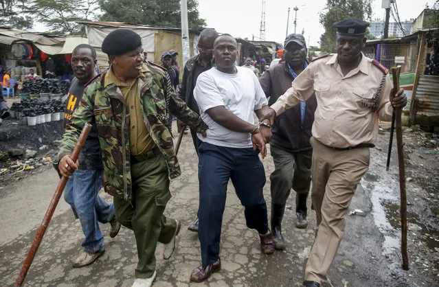 Security forces arrest a man for operating a restaurant serving food to customers eating on the premises, which has been prohibited and only takeaways are allowed under measures aimed at halting the spread of the new coronavirus, in Nairobi, Kenya Friday, March 27, 2020. (Photo by Brian Inganga/AP Photo)