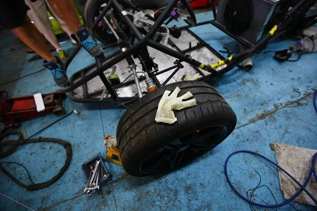 A glove is seen on a tyre after being assembled onto a replica of T-rex motorcycle by Wang Yu and Li Lintao at a garage on the outskirts of Beijing, August 21, 2014. (Photo by Petar Kujundzic/Reuters)