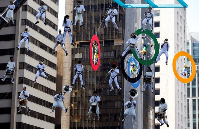 Acrobats on Olympics rings and lifted musicians perform as the Olympic torch is relayed along Paulista Avenue in Sao Paulo's financial center, Brazil, July 24, 2016. (Photo by Paulo Whitaker/Reuters)