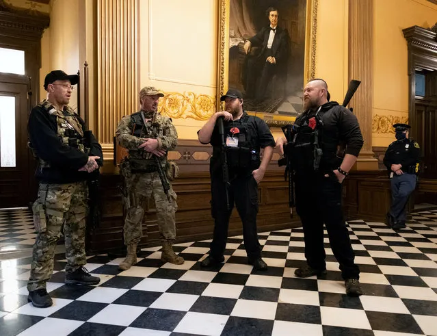 Members of a militia group stand near the doors to the chamber in the capitol building before the vote on the extension of Governor Gretchen Whitmer's emergency declaration/stay-at-home order due to the coronavirus disease (COVID-19) outbreak, in Lansing, Michigan, U.S. April 30, 2020. (Photo by Seth Herald/Reuters)