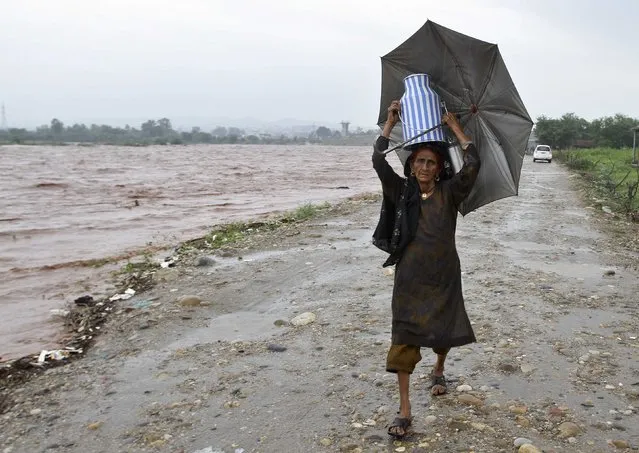 A nomadic woman carries a milk container while shifting her belongings to a safer place from the flooded banks of river Tawi after heavy rains in Jammu September 5, 2014. Sixty-five people were killed after heavy rains caused flash floods in Indian-administered Kashmir, including a wedding party on a bus that was swept away, officials said on Thursday. (Photo by Mukesh Gupta/Reuters)