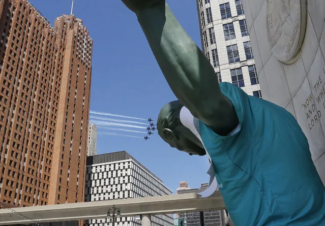 The Spirit of Detroit statue by Marshall Fredericks,  wearing a white ribbon to honor essential workers, first responders and healthcare professionals, is seen as the Blue Angels, the U.S. Navy's flight demonstration squadron, fly over Detroit, Tuesday, May 12, 2020. The flyover was a salute to front line workers in the wake of the coronavirus pandemic. (Photo by Carlos Osorio/AP Photo)