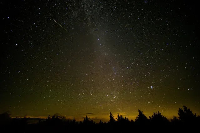 In this 30 second exposure, a meteor streaks across the sky during the annual Perseid meteor shower Friday, August 12, 2016 in Spruce Knob, W. Va.  Scientists call this an outburst, and they say it could reach up to 200 meteors per hour. (Photo by Bill Ingalls/NASA via AP Photo)