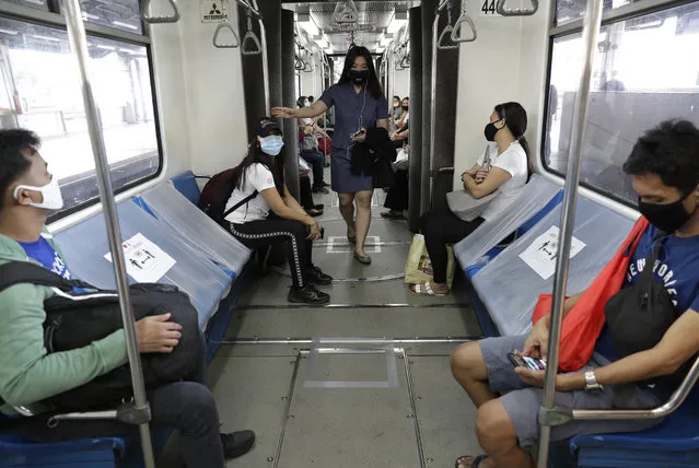 People board a train with seats arranged for social distancing measures to help curb the spread of the coronavirus during the first day of a more relaxed lockdown in Manila, Philippines on Monday, June 1, 2020. Traffic jams and crowds of commuters are back in the Philippine capital, which shifted to a more relaxed quarantine with limited public transport in a high-stakes gamble to slowly reopen the economy while fighting the coronavirus outbreak. (Photo by Aaron Favila/AP Photo)