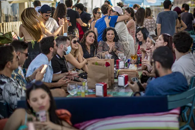 People enjoy in a snack bar in Barcelona, Spain, Sunday, June 21, 2020. Spain ended a national state of emergency after three months of lockdown, allowing its 47 million residents to freely travel around the country for the first time since March 14. The country also dropped a 14-day quarantine for visitors from Britain and the 26 European countries that allow visa-free travel. (Photo by Emilio Morenatti/AP Photo)