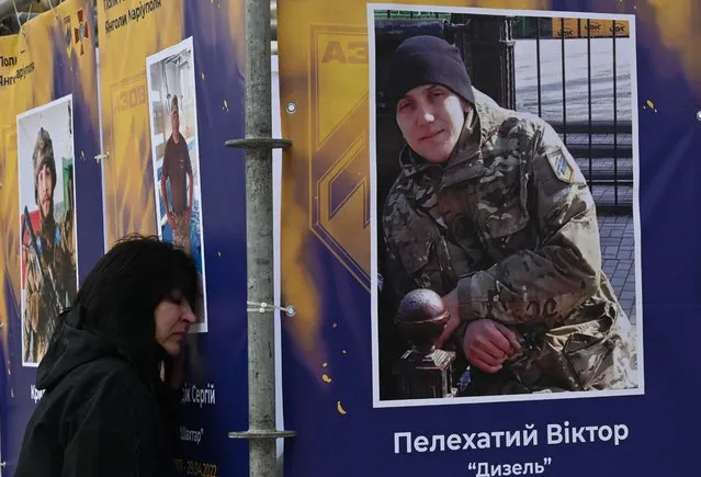 A woman, relinive of a dead serviceman, reacts at his portrait during the opening of an open-air exhibition “Azov Regiment – Angels of Mariupol” in the centre of Kyiv to mark Ukraine's Defenders Day on October 14, 2022, amid the Russian invasion of Ukraine. Ukraine's President Volodymyr Zelensky promised on October 14, the victory over Russia as his country celebrated its first Defenders Day public holiday since the start of Moscow's invasion almost eight months ago. Defenders Day was established in 2014 to replace a previous February 23 holiday of Soviet origin that is still celebrated in Russia. (Photo by Sergei Supinsky/AFP Photo)