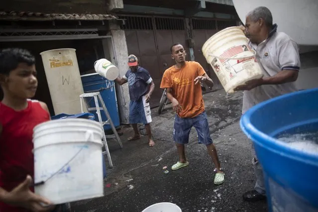 Residents form a bucket brigade, filling large containers with water provided by a government water truck, in the Petare slum of Caracas, Venezuela, Wednesday, June 10, 2020. Amid water shortages during the COVID-19 pandemic, the government is providing free water to some areas. (Photo by Ariana Cubillos/AP Photo)