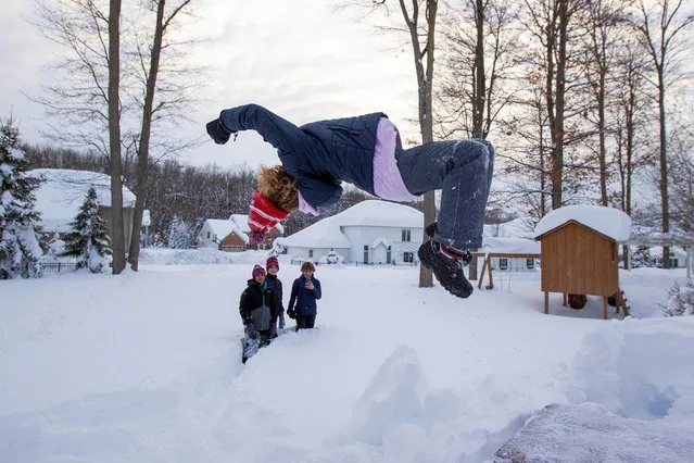 Gavin Reashor does a backflip into the snow while his friends look on during a break in the snow storm hitting the Buffalo area, in Orchard Park, New York, U.S. November 19, 2022. (Photo by Carlos Osorio/Reuters)