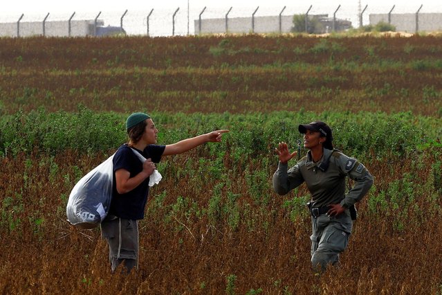 Israeli border police stop a man from heading to a protest against the delivery of humanitarian aid to Gaza and demand the immediate release of Israeli hostages kidnapped in the deadly October 7 attack, as trucks waiting to enter Gaza from Egypt are seen in the background, amid the ongoing conflict between Israel and the Palestinian Islamist group Hamas, at the Kerem Shalom Crossing, Israel, on February 20, 2024. (Photo by Susana Vera/Reuters)