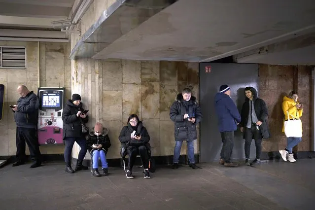 People use their phones while they gather in a metro station during an air raid alarm, in Kyiv, Ukraine, Wednesday, December 21, 2022. (Photo by Felipe Dana/AP Photo)