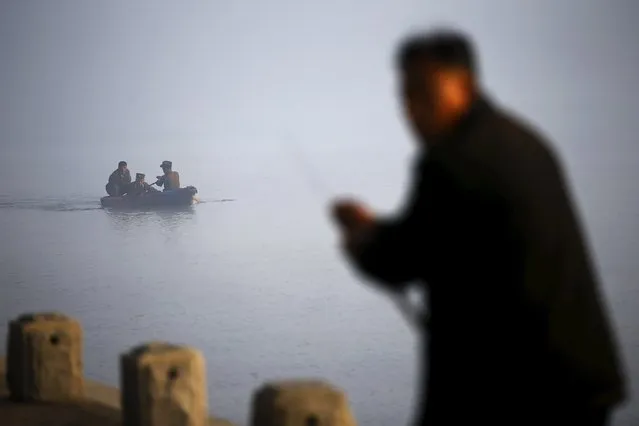 A man fishes as North Korean military personnel paddle a small boat amid morning fog over Taedong River in Pyongyang October 8, 2015. One of the world's most inaccessible places, North Korea has invited foreign journalists to Pyongyang this week for celebrations marking the 70th anniversary of its ruling Workers' Party, and rising wealth is evident despite a creaking state economy. (Photo by Damir Sagolj/Reuters)