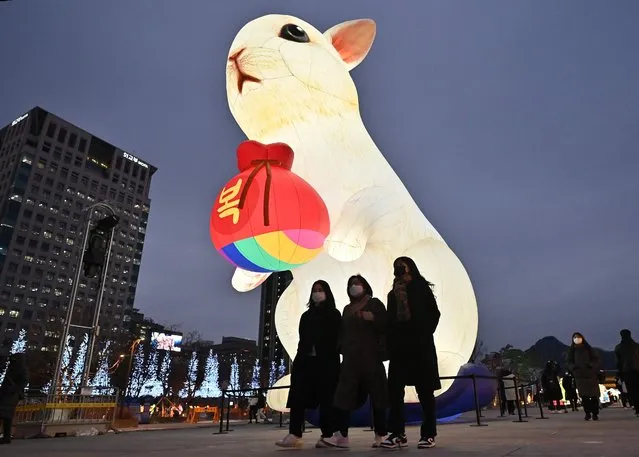 People walk past an illuminated lantern for the upcoming Year of the Rabbit during Seoul Lantern Festival at Gwanghwamun square in Seoul on December 19, 2022. (Photo by Jung Yeon-je/AFP Photo)