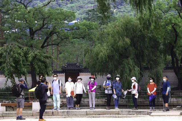 Visitors wearing face masks to help protect against the spread of the coronavirus pose to take pictures at the Gyeongbok Palace in Seoul, South Korea, Monday, August 17, 2020. South Korea counted its fourth straight day of triple-digit increases in new coronavirus cases Monday as the government urged people to stay home and curb travel. (Photo by Ahn Young-joon/AP Photo)