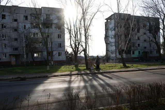 People walk through the partially destroyed town of Borodianka on January 02, 2023 in Borodianka, Ukraine. Borodianka, northwest of the Ukrainian capital, came under heavy air-strike and artillery bombardment by Russian forces as they tried to seize Kyiv early in their invasion of Ukraine. Once Russian forces withdrew at the end of March, many of its residential buildings lay in ruins. (Photo by Spencer Platt/Getty Images)