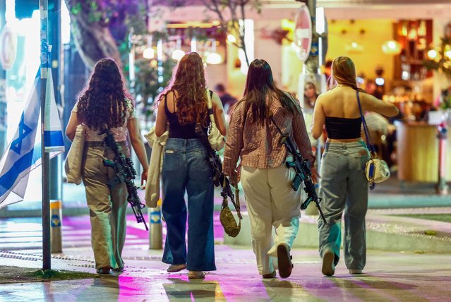 Women carrying rifles walk on Dizengoff Square in Tel Aviv, Israel on October 28, 2024. (Photo by Gonzalo Fuentes/Reuters)