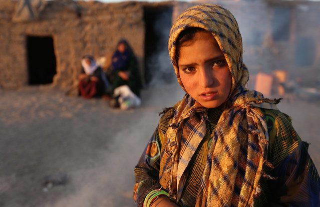 A young internally displaced from Faryab province poses for a picture near her temporary shelter at an Internally Displaced Persons (IDPs) camp on the outskirts of Herat, Afghanistan, 13 October 2015. According to UN Refugee Agency (UNHCR) figures, the number of internally displaced Afghani people was 683,000 by mid-2014, estimating they will amount to 900,000 by the end of 2015. (Photo by Jalil Rezayee/EPA)