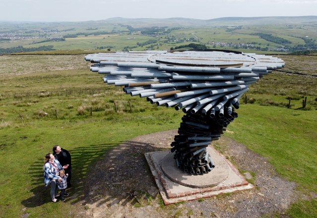 Migle Politike (left) with son Aaron and friend Goda Zubkaityte on Wednesday, June 11, 2025 stop to look at the Singing Ringing Tree, a musical sculpture designed to look like a windswept tree, at Crown Point overlooking Burnley, Lancashire, UK. The wind-powered musical sculpture emits a low, tuneful song when the wind blows. (Photo by Martin Rickett/PA Wire)