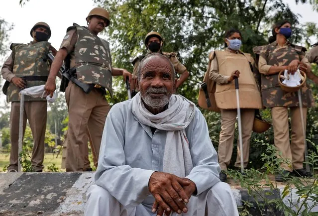 A farmer rests as police officers stand guard during a protest against farm bills passed by India's parliament, at the Delhi-Uttar Pradesh border, in New Delhi, India, September 25, 2020. (Photo by Danish Siddiqui/Reuters)