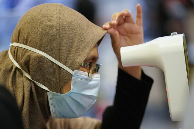 A Muslim women wearing a face mask to help curb the spread of the coronavirus measures her temperature at a shopping mall in Putrajaya, Malaysia, Thursday, October 1, 2020. Thursday's new COVID-19 infections made it the second highest increase since the recovery movement control order (MCO) phase began on June 9. (Photo by Vincent Thian/AP Photo)