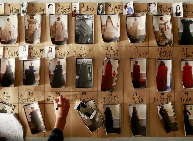 A staff arranges photos of models in their clothes backstage before the fashion show of ECHO CHEN Collection at China Fashion Week S/S 2016 in Beijing, October 26, 2015. (Photo by Kim Kyung-Hoon/Reuters)