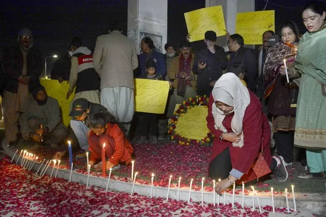 Children light candle as they with other take part in a candle light vigil for the victims of Monday's suicide bombing, called by a civil society group, in Quetta, Pakistan, February 2, 2023. A suicide bomber who killed 101 people at a mosque in northwest Pakistan this week had disguised himself in a police uniform and did not raise suspicion among guards, the provincial police chief said on Thursday. (Photo by Arshad Butt/AP Photo)