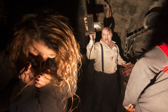 Actor Robert Butcher scares guests with an bladeless circular saw at the The Dent Schoolhouse haunted attraction, Thursday, October 29, 2015, in Cincinnati.  The haunt, owned and operated by Bud Stross and Josh Wells, two high school friends, inhabits a late 19th century schoolhouse they've renamed "The Dent Schoolhouse". (Photo by John Minchillo/AP Photo)