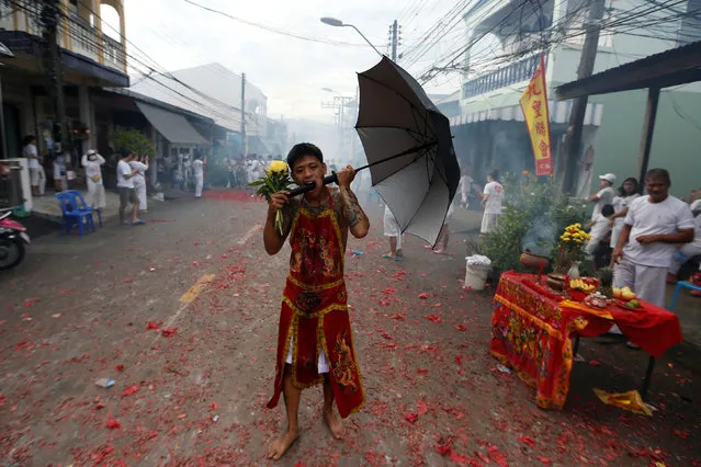 A devotee of the Chinese Bang Neow shrine with an umbrella handle pierced through his cheek takes part in a procession celebrating the annual vegetarian festival in Phuket, Thailand October 6, 2016. (Photo by Jorge Silva/Reuters)