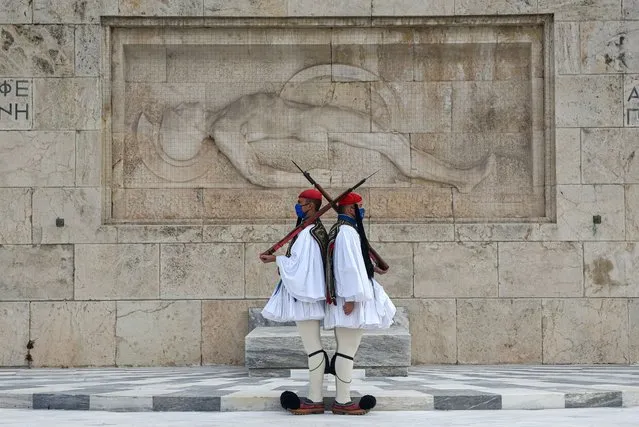 Greek Presidential Guards, the Evzones, wear protective masks against the spread of coronavirus while performing their ceremonial duties at the Tomb of the Unknown Soldier on November 22, 2020 in Athens, Greece. Greek authorities aim to lift some of the current restrictions, which include the closure of schools and non-essential shops, when the lockdown expires on December 7. The lockdown was imposed on November 7 to curb a rise in coivd-19 cases. (Photo by Milos Bicanski/Getty Images)