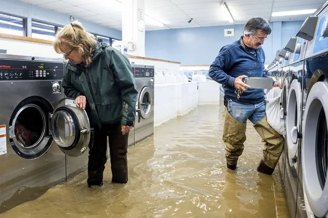 Pamela and Patrick Cerruti empty coins from Pajaro Coin Laundry as floodwaters surround machines in the community of Pajaro in Monterey County, Calif., Tuesday, March 14, 2023. “We lost it all. That's half a million dollars of equipment”, said Pamela who added that they plan to rebuild. (Photo by Noah Berger/AP Photo)