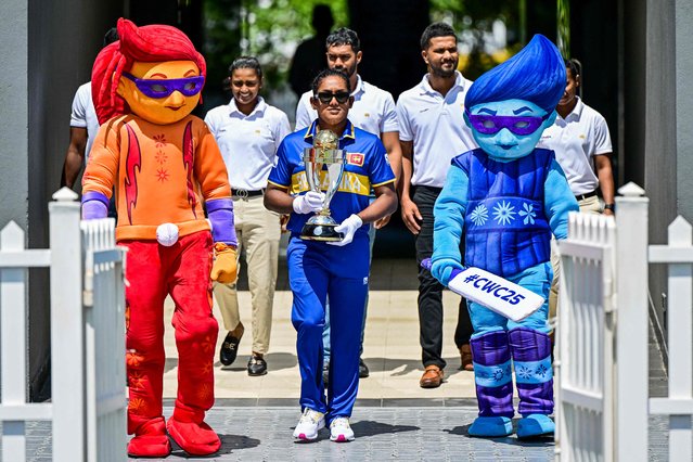 Sri Lanka's captain Chamari Athapaththu (C) holds the 2025 ICC Women's Cricket World Cup trophy as she walks alongside mascots Blaze (L) and Tonk during the trophy unveiling ceremony at the R. Premadasa International Cricket Stadium in Colombo on September 22, 2025. (Photo by Ishara S. Kodikara/AFP Photo)