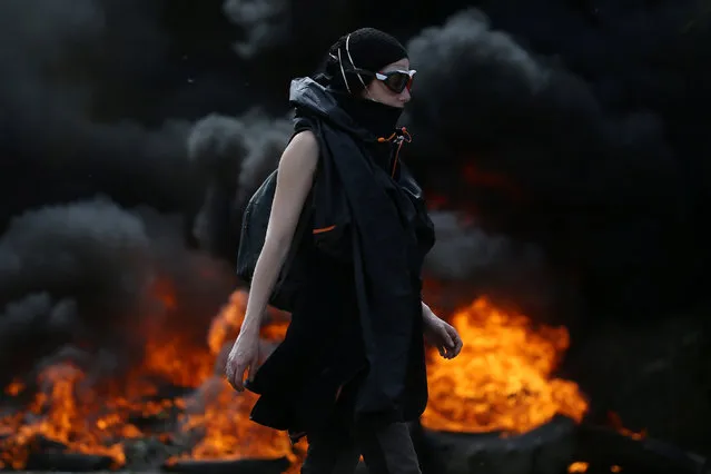 A protester walks near burning debris that barricades a road as French gendarmes continue an evacuation operation in the zoned ZAD (Deferred Development Zone) at Notre-Dame-des-Landes, near Nantes, France, April 12, 2018. (Photo by Stephane Mahe/Reuters)