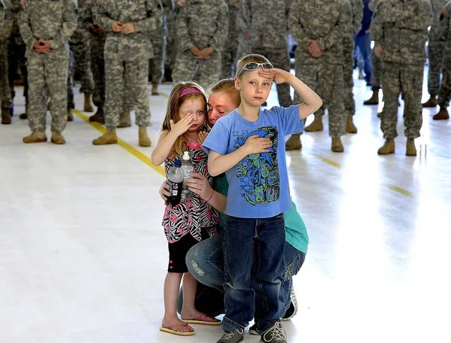 C. J. Richards, 6, salutes while his aunt, Sgt. Ashley Corey, prepares for deployment to Afghanistan as the Michigan Army National Guard Charlie Company 3/238th General Support Aviation Battalion leaves Grand Ledge, on May 1, 2013. Behind C.J., Corey's mother, Della Corey, comforts Aaryon Johnson, 3, a niece of Sgt. Corey. (Photo by Rod Sanford/The State Journal)