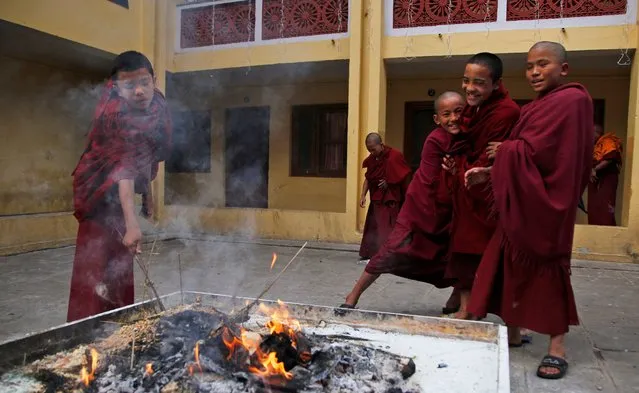 Young Buddhist monks play standing next to a fire at a monastery in Boudhanath stupa, Kathmandu, Nepal, Friday, December 11, 2020. The stupa is an important pilgrimage site for Buddhists. (Photo by Niranjan Shrestha/AP Photo)