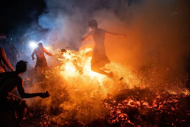Balinese man kicks burn coconut husks during the fire fight ritual called Mesabatan Api on March 21, 2023 at traditional sub village of Nagi, in Gianyar, Bali, Indonesia. The mesabatan api ritual is held annually on the eve of Nyepi, the Hindu Day of Silence, the Balinese Caka New Year, and only takes place in Pakraman Nagi village in Gianyar regency, around 30 kilometers from Denpasar. (Photo by Agung Parameswara/Getty Images)