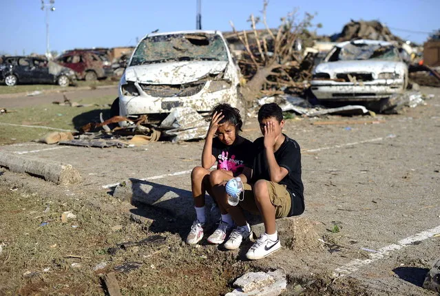 Plaza Towers Elementary School students Monica Boyd (L) and Lavontey Rodriguez sit at the parking lot of their tornado devastated school on May 22, 2013 in Moore, Oklahoma. Seven children died in the school during the tornado. As rescue efforts in Oklahoma wound down, residents turned to the daunting task of rebuilding a US heartland community shattered by a vast tornado that killed at least 24 people. The epic twister, two miles (three kilometers) across, flattened block after block of homes as it struck mid-afternoon on May 20, hurling cars through the air, downing power lines and setting off localized fires in a 45-minute rampage. (Photo by Jewel Samad/AFP Photo)