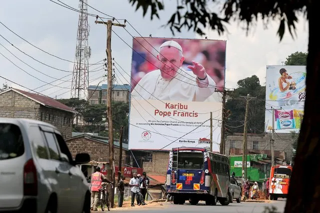 People stand below large poster of Pope Francis in Nairobi, Kenya, November 24, 2015. (Photo by Goran Tomasevic/Reuters)