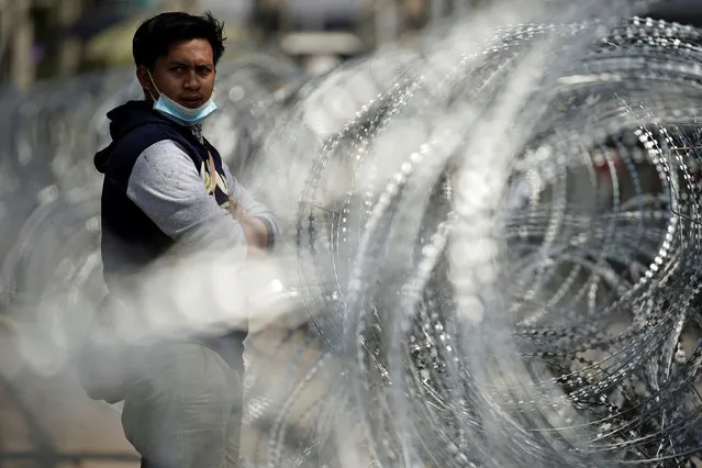 A migrant worker stands next to barbed wire in front of a closed shrimp market, amid the coronavirus disease (COVID-19) outbreak, in Samut Sakhon province, in Thailand, December 20, 2020. (Photo by Athit Perawongmetha/Reuters)