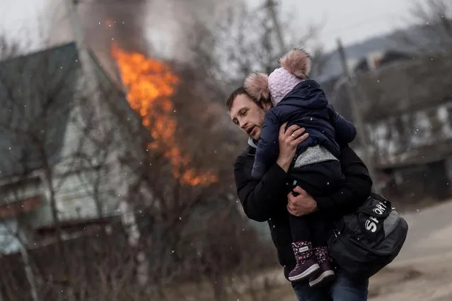 A man and a child escape from the town of Irpin, after heavy shelling on the only escape route used by locals, while Russian troops advance towards the capital of Kyiv, in Irpin, near Kyiv, Ukraine on March 6, 2022. (Photo by Carlos Barria/Reuters)